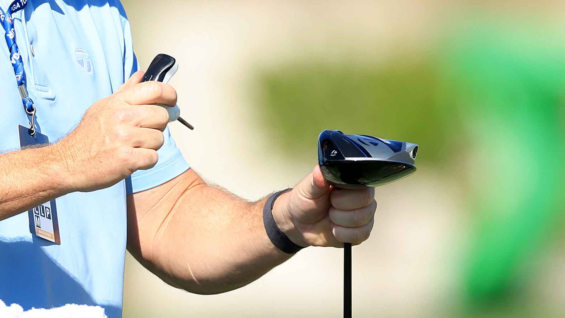 Tiger Woods of The United States adjusts his new driver with the assistance of a Taylor Made member of staff during practice as a preview for the Hero World Challenge